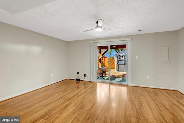 spare room with light wood-style floors, a ceiling fan, baseboards, and a textured ceiling