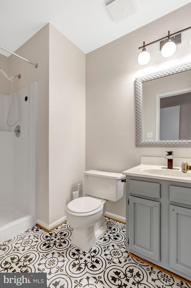 bathroom featuring a shower, tile patterned flooring, vanity, and toilet