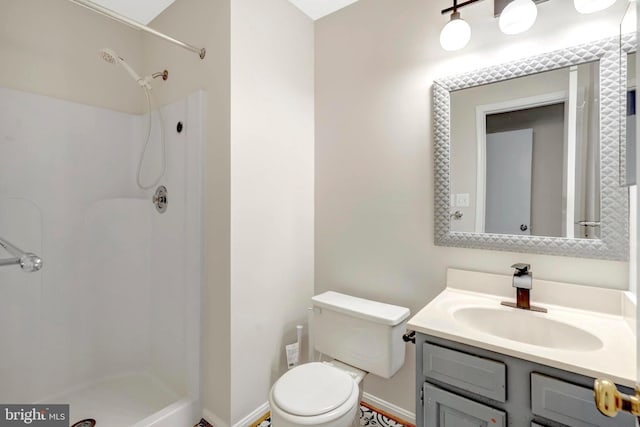 bathroom with toilet, baseboards, walk in shower, and vanity