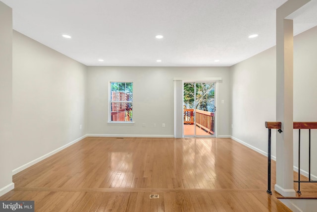 unfurnished room with a wealth of natural light, baseboards, and hardwood / wood-style floors