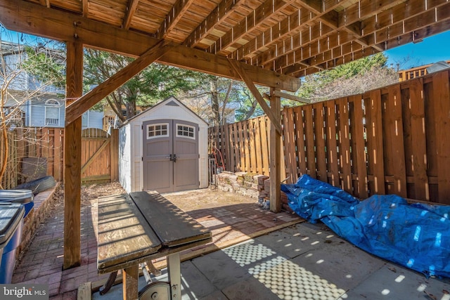 view of patio / terrace featuring a shed, a gate, a fenced backyard, and an outbuilding