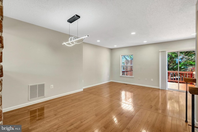 interior space featuring recessed lighting, visible vents, light wood-style flooring, a textured ceiling, and baseboards