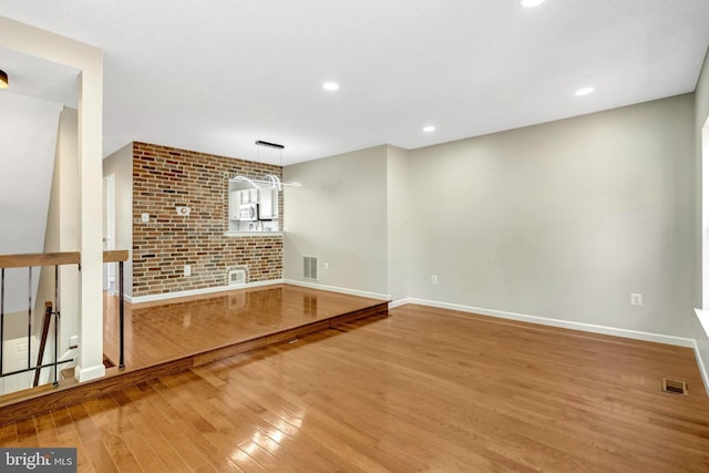 unfurnished living room featuring visible vents, baseboards, and hardwood / wood-style flooring