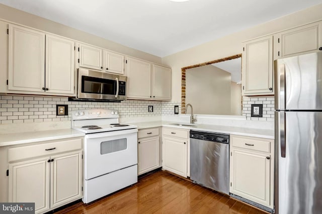 kitchen with dark wood-style flooring, stainless steel appliances, light countertops, backsplash, and a sink