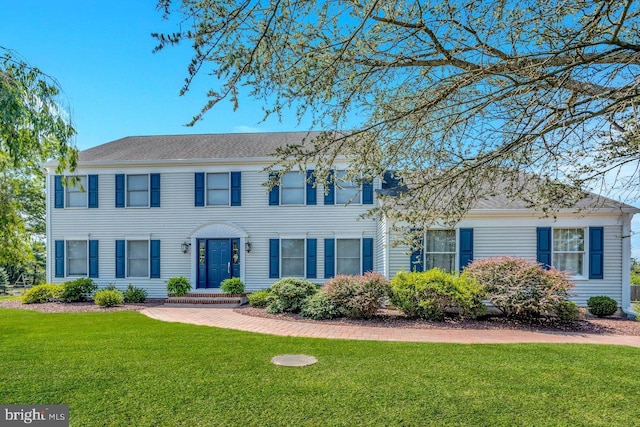 colonial-style house featuring a front yard