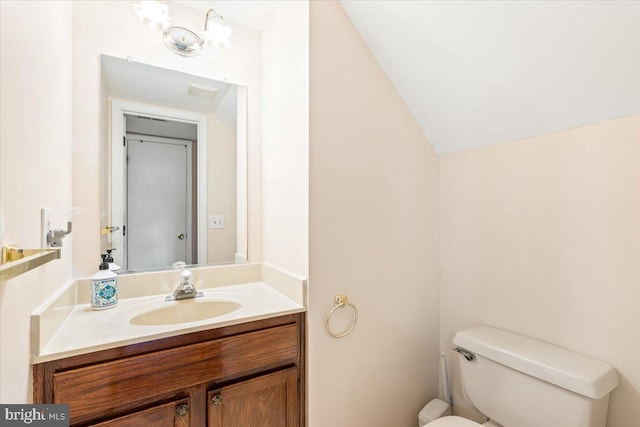 half bathroom featuring visible vents, lofted ceiling, toilet, and vanity