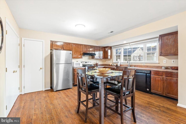 kitchen featuring visible vents, under cabinet range hood, dark wood-style flooring, stainless steel appliances, and a sink