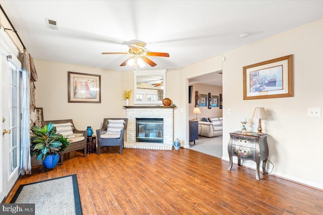 sitting room with a healthy amount of sunlight, a brick fireplace, and wood finished floors