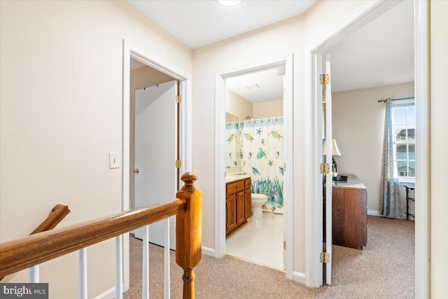 hall featuring light carpet, an upstairs landing, and baseboards