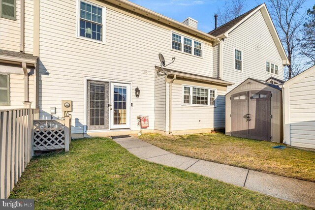 back of house featuring an outbuilding, a yard, french doors, a storage shed, and a chimney