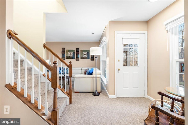 carpeted foyer featuring stairway and baseboards