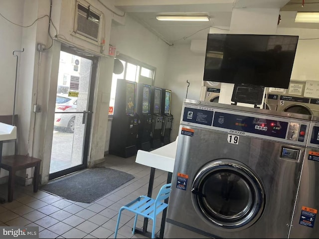 community laundry room featuring stacked washer / dryer, a wall mounted AC, and tile patterned floors