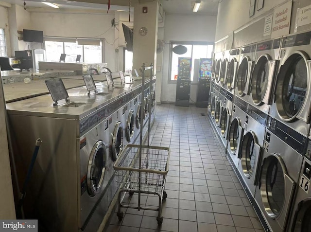 community laundry room with stacked washer and dryer, tile patterned flooring, and washer and clothes dryer