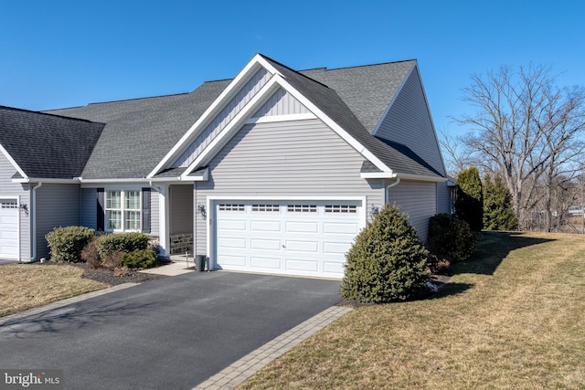 view of front facade featuring aphalt driveway, a shingled roof, board and batten siding, a front yard, and a garage