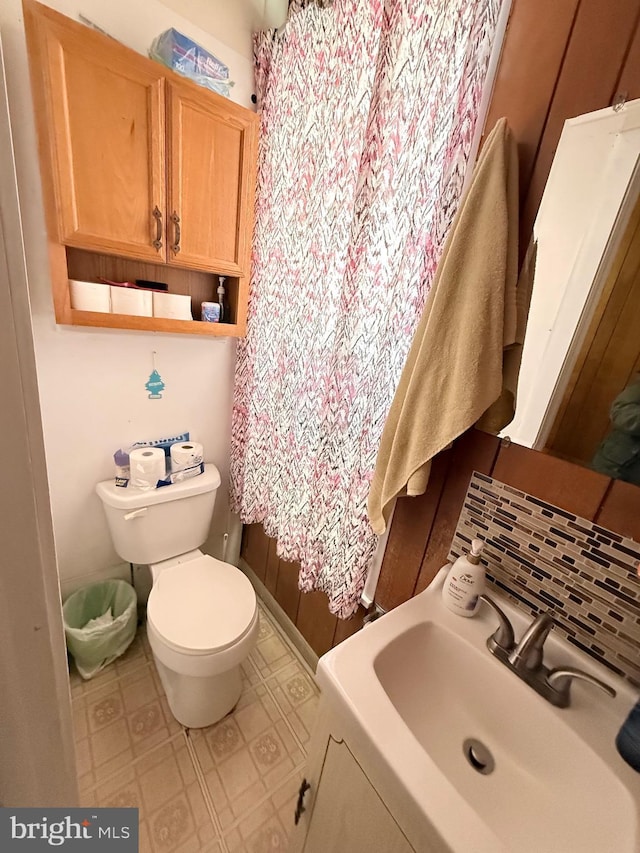 bathroom featuring toilet, backsplash, a sink, and tile patterned floors