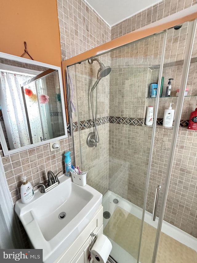 full bathroom with a shower stall, tile walls, backsplash, and a sink