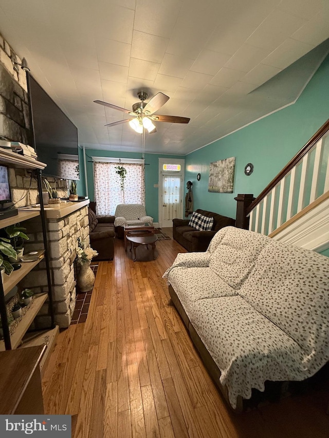 living area with a fireplace, ceiling fan, and hardwood / wood-style flooring