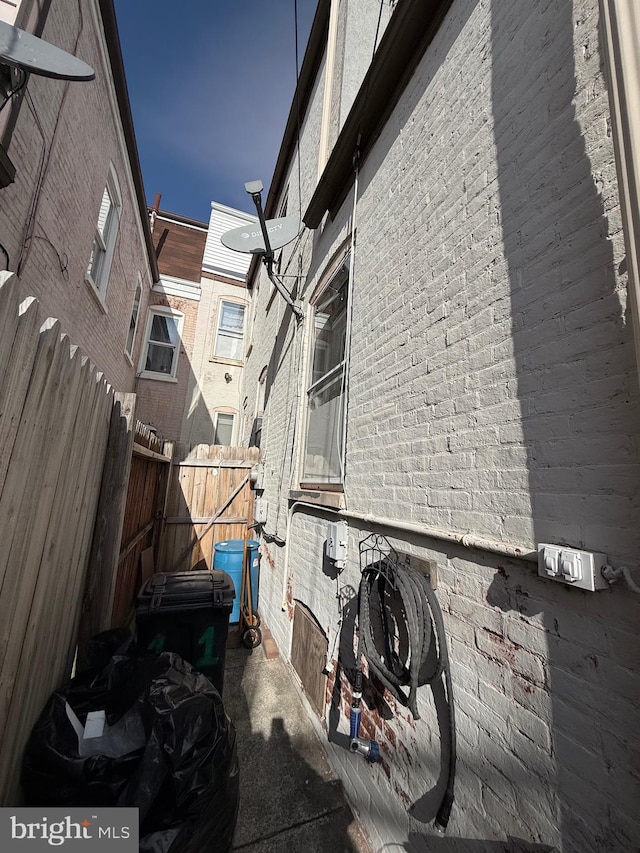 view of side of property with brick siding and fence