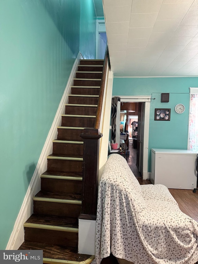 staircase featuring wood finished floors and baseboards