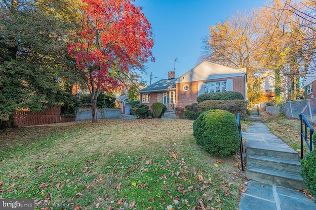 bungalow-style home with brick siding, fence, a chimney, and a front lawn