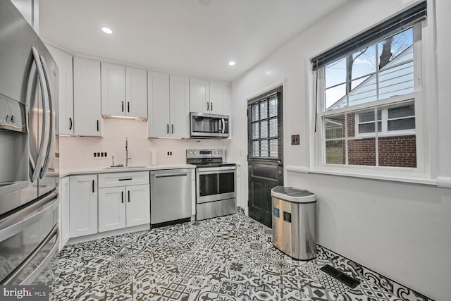 kitchen featuring appliances with stainless steel finishes, a sink, and white cabinetry