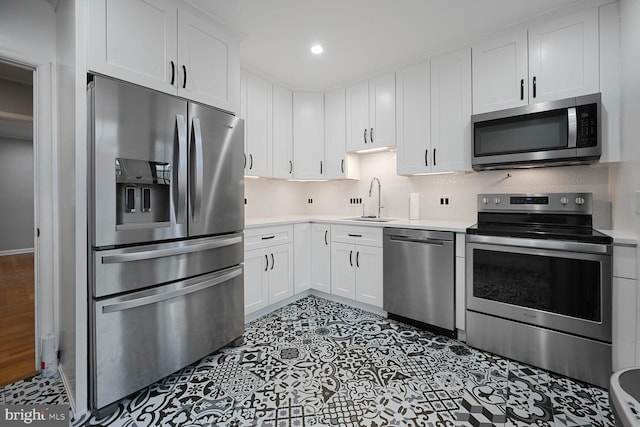 kitchen with stainless steel appliances, white cabinets, light countertops, and backsplash