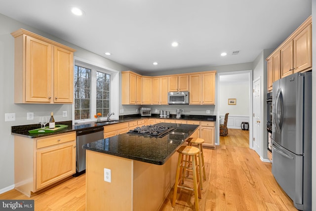 kitchen with stainless steel appliances, light wood finished floors, light brown cabinets, and visible vents