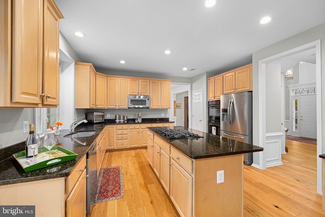 kitchen with a center island, light wood-style flooring, appliances with stainless steel finishes, light brown cabinets, and a sink