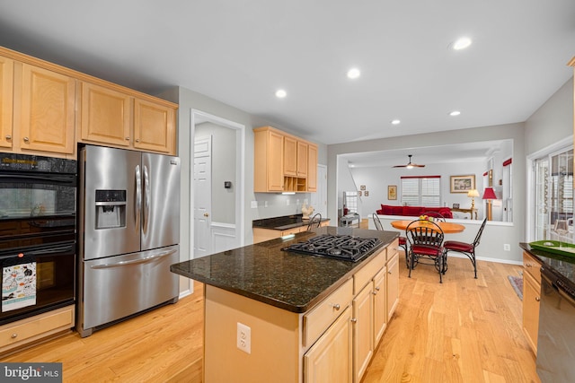 kitchen with light brown cabinets, light wood-style flooring, recessed lighting, a center island, and black appliances