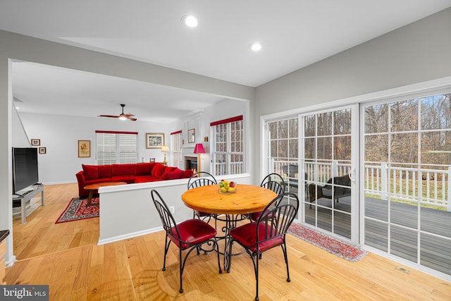 dining area with light wood-style flooring, a fireplace, ceiling fan, and recessed lighting