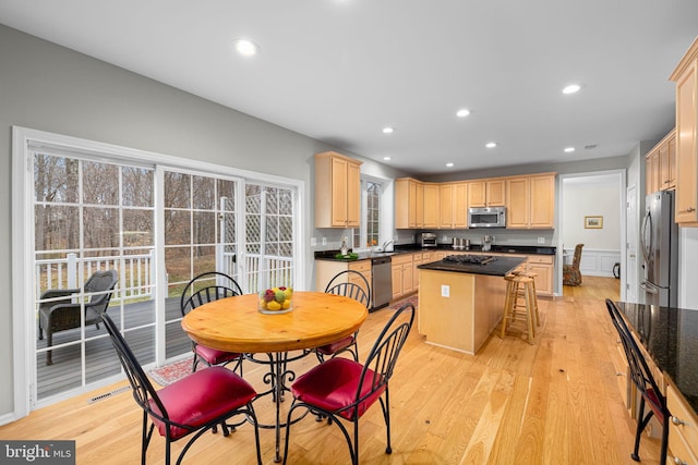 kitchen featuring stainless steel appliances, light brown cabinetry, light wood-type flooring, and a kitchen island