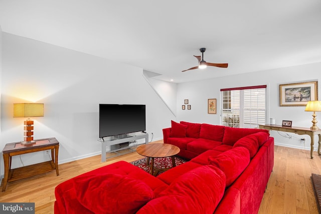 living area featuring a ceiling fan, baseboards, and wood finished floors