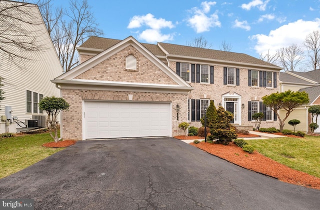 colonial home with brick siding, central air condition unit, a garage, driveway, and a front lawn