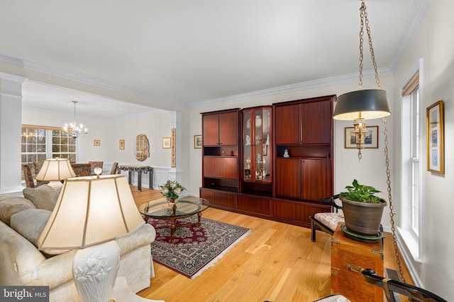 living area featuring a chandelier, light wood-type flooring, and crown molding