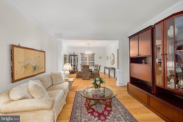 living room with a chandelier, light wood-type flooring, ornamental molding, and ornate columns