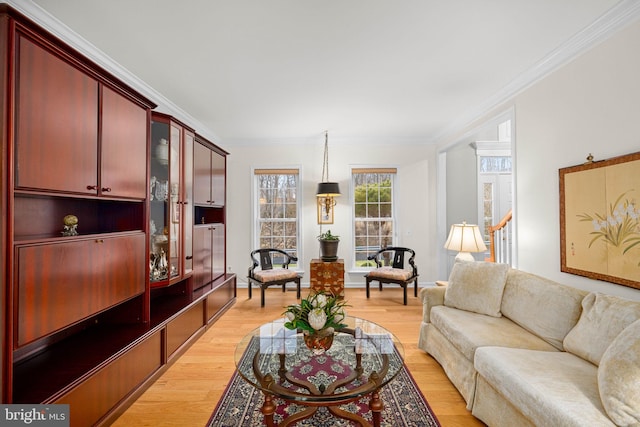 living room featuring light wood-style flooring, stairs, and crown molding