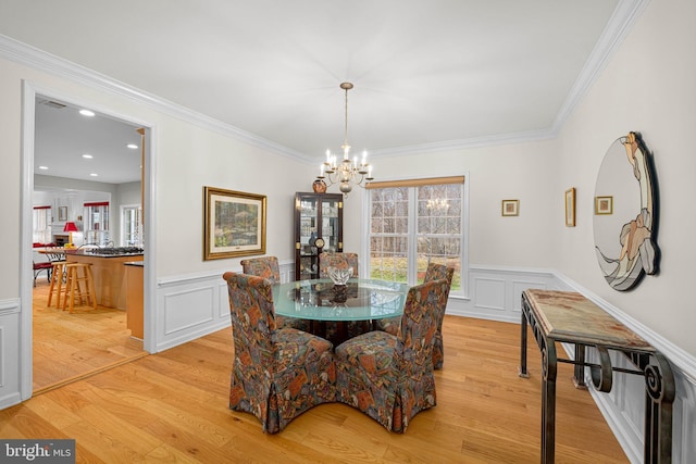 dining area with light wood-style flooring, a chandelier, and ornamental molding