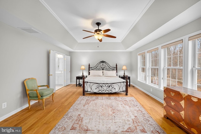 bedroom featuring light wood-type flooring, visible vents, a tray ceiling, and ornamental molding