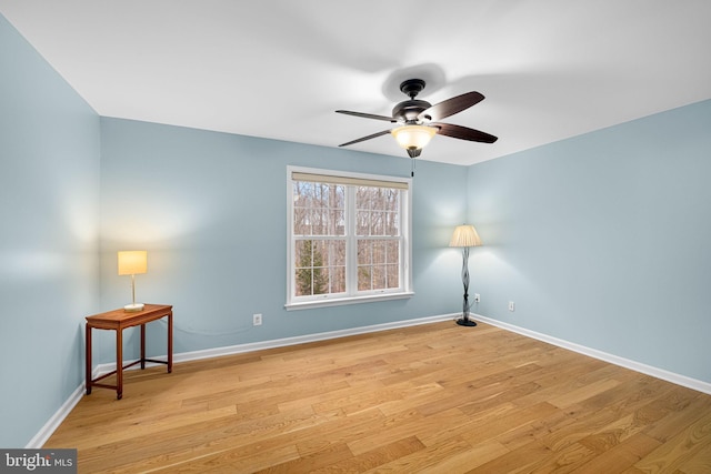 spare room with light wood finished floors, ceiling fan, and baseboards