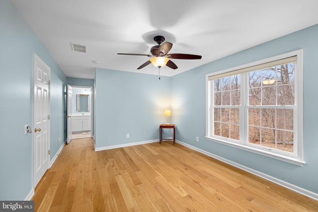 unfurnished bedroom with light wood-style flooring, connected bathroom, visible vents, and baseboards