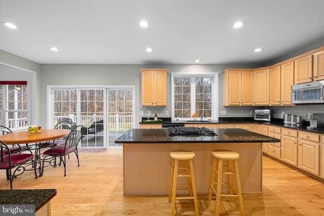 kitchen with light wood-style flooring, stainless steel microwave, light brown cabinets, black gas stovetop, and recessed lighting