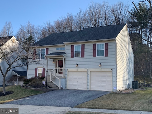 split foyer home with central AC unit, a garage, driveway, roof with shingles, and a front lawn