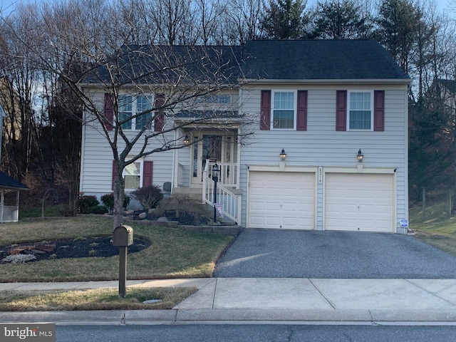 raised ranch featuring aphalt driveway, a garage, and a front yard