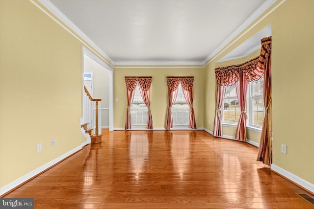 spare room featuring wood-type flooring, stairs, baseboards, and crown molding