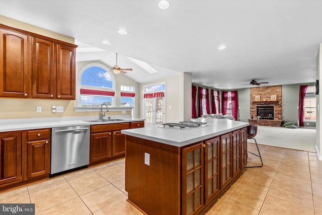 kitchen featuring light tile patterned flooring, a fireplace, a sink, dishwasher, and plenty of natural light