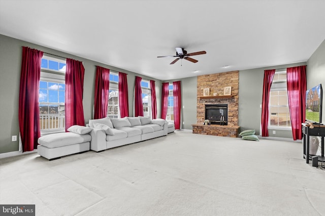 living area featuring ceiling fan, a fireplace, carpet flooring, and baseboards