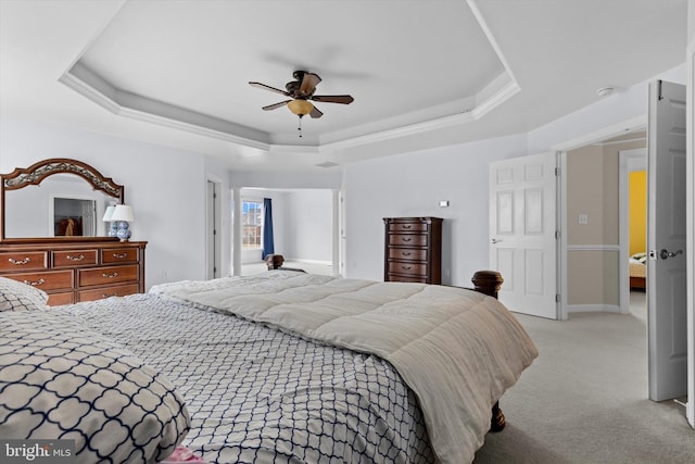 bedroom featuring light carpet, a tray ceiling, a ceiling fan, and baseboards