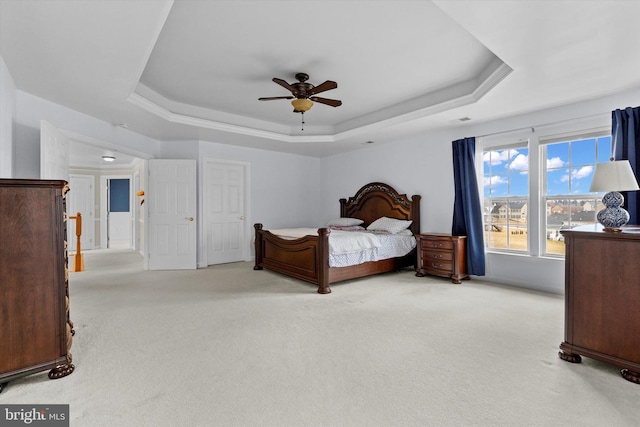 bedroom featuring light carpet, ceiling fan, visible vents, and a raised ceiling