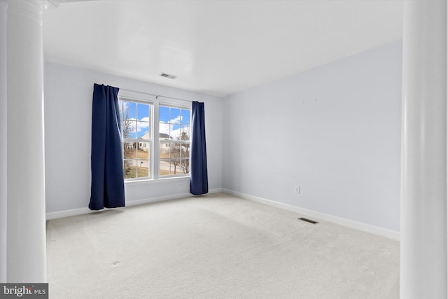 carpeted spare room featuring visible vents, decorative columns, and baseboards