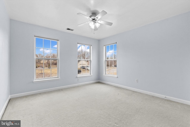 carpeted empty room featuring visible vents, ceiling fan, and baseboards